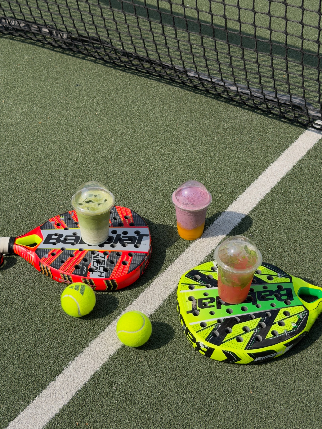 Colourful smoothies arranged on padel rackets courtside