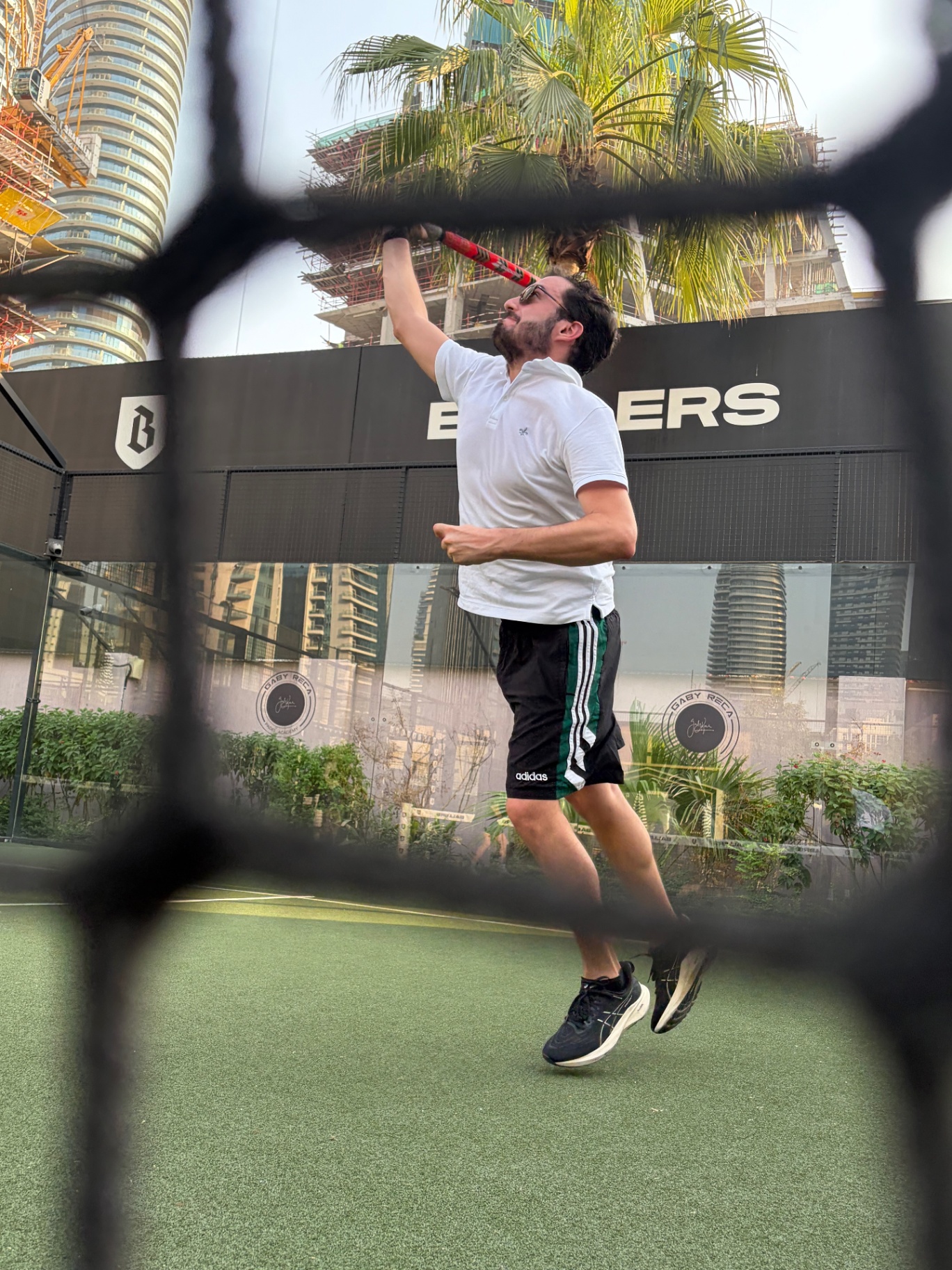 Padel player in action on court at Ballers Dubai